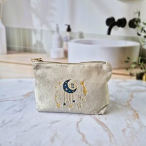 Front view of the Ciel des Rêves Petite Makeup Bag in Amoonstone beige velvet, featuring moon, stars, and evil eye embroidery in blue, gold, and cream.