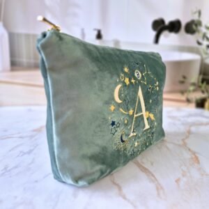 Side view of the Aqua Marine teal velvet pouch with the letter "A" embroidered alongside gold and blue celestial details, Ciel des Rêves collection by Edoaria.