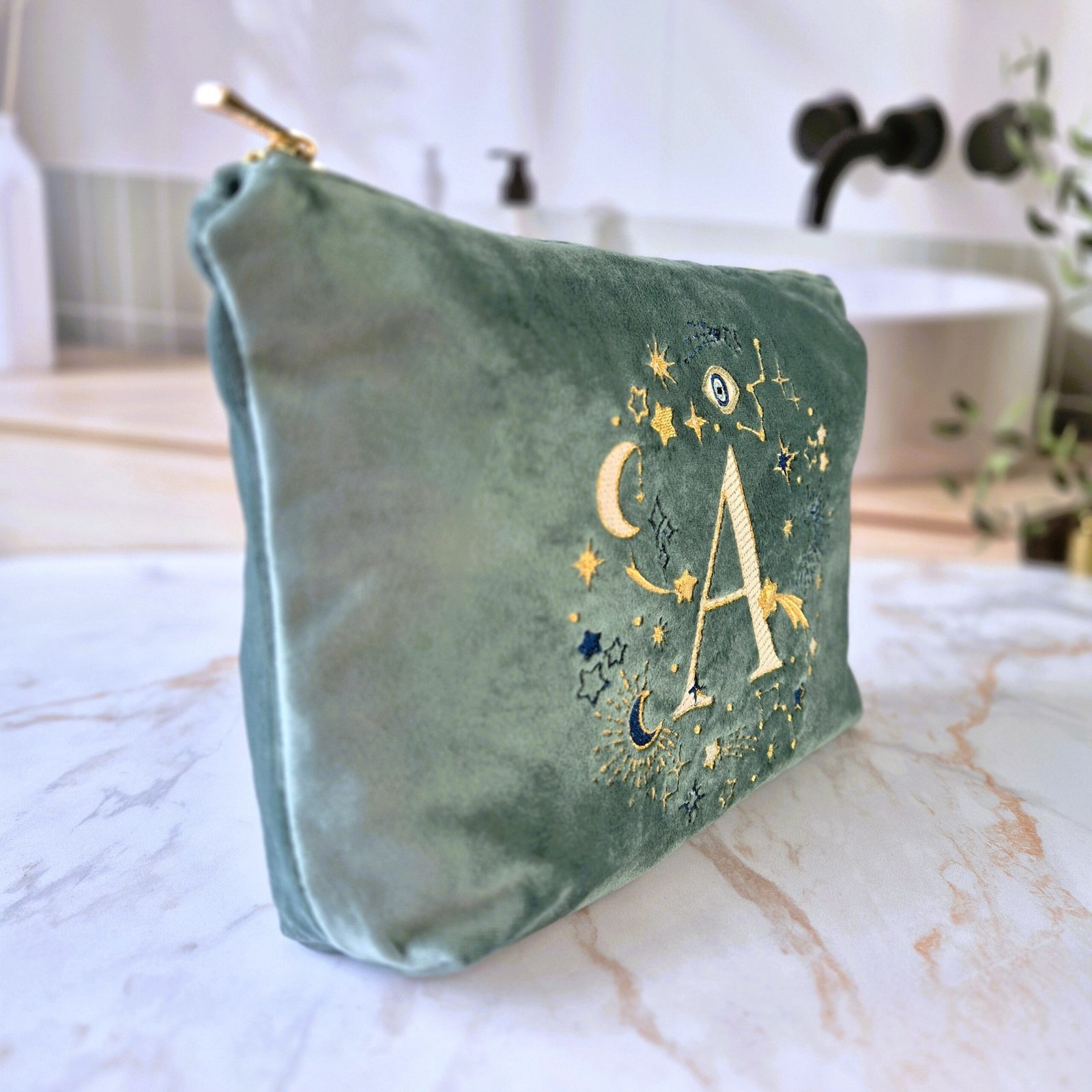 Side view of the Aqua Marine teal velvet pouch with the letter "A" embroidered alongside gold and blue celestial details, Ciel des Rêves collection by Edoaria.