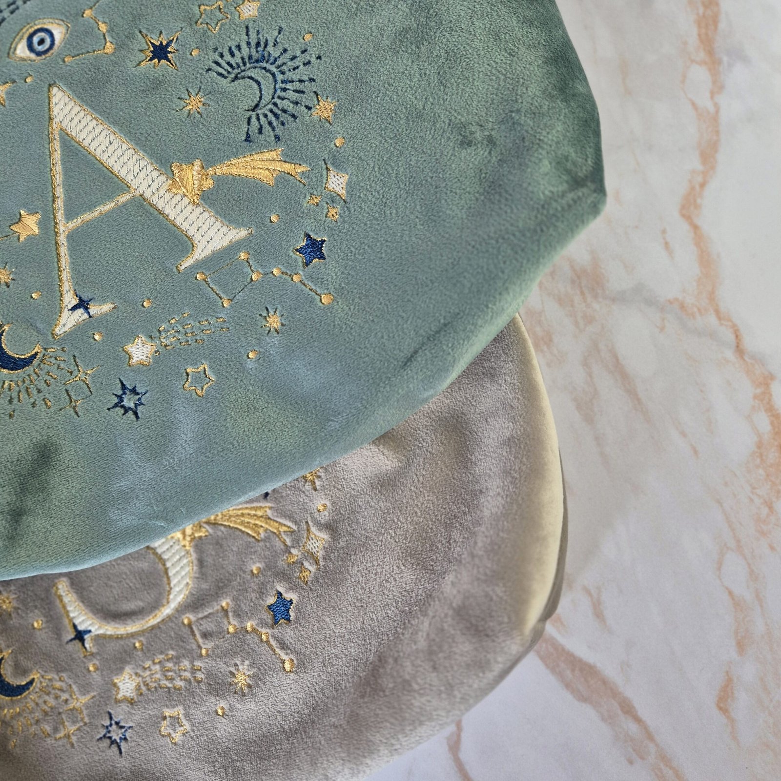 Ciel des Rêves Velvet Pouch – Teal Aqua Marine andBeige Moonstone with Gold and Blue Embroidery Edoaria Ciel des Rêves Bags elegantly placed on a mable top counter bathroom, creating a luxurious and pampering setting.