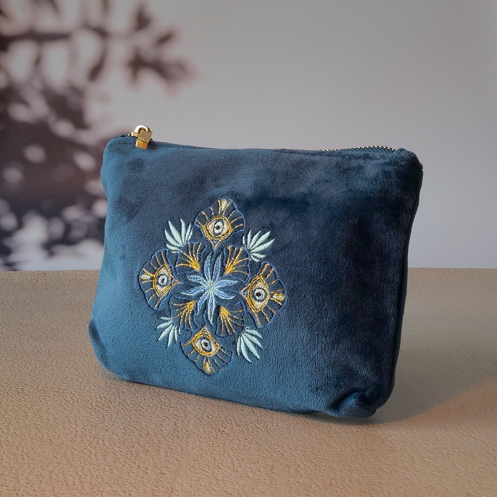 Petite trousse de maquillage - Broderie géométrique et protectrice Side view of the Petite Makeup Bag, highlighting its intricate symmetrical embroidery in blue, turquoise, and gold.