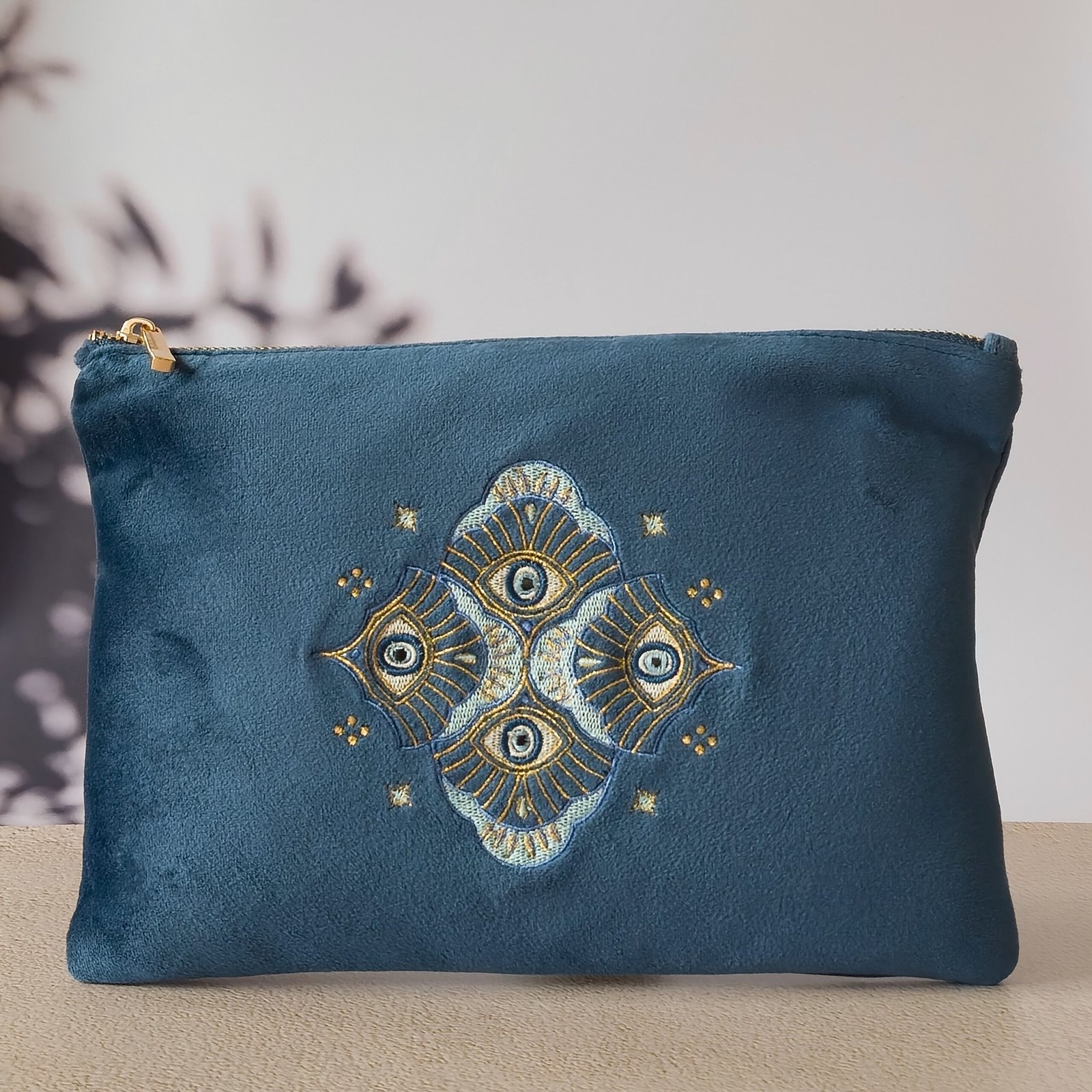 Jardin des Cyclades Signature Sleek Pouch - Broderie Arabesque et Oeil maléfique A sapphire blue velvet Signature Sleek Pouch with intricate Arabesque and protective Evil Eye embroidery.