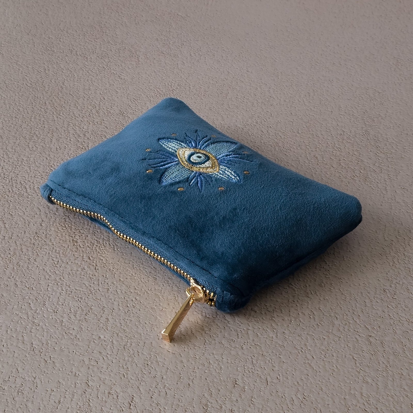A close-up of the gold zipper on the Essentials Sleek Pouch, with soft sapphire blue velvet.