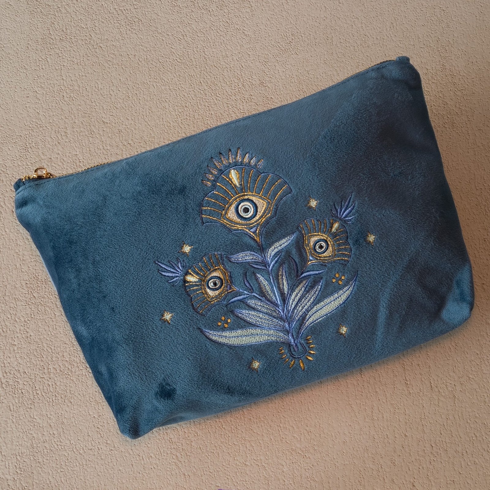 The Grand Toiletry Bag laid flat, showcasing its symmetrical floral embroidery with Greek evil eye details.