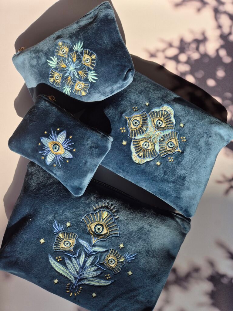 Collection EDOARIA "Jardin des Cyclades" mêlant des designs floraux art nouveau Belge et l'oeil protecteur mati Grec. Trousses en velours bleu et brodées.